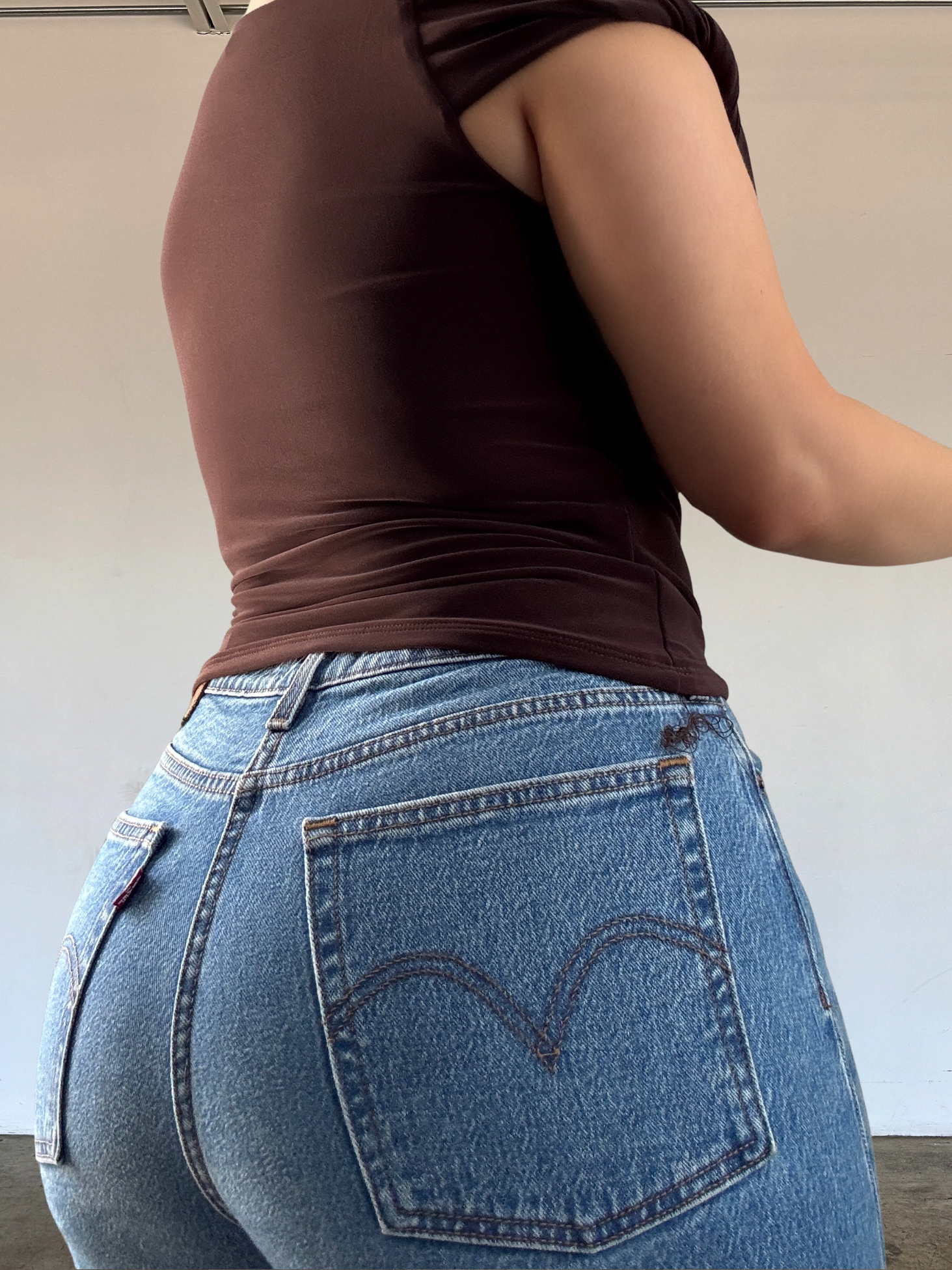 Person wearing blue jeans with Levi's logo on a plain background
